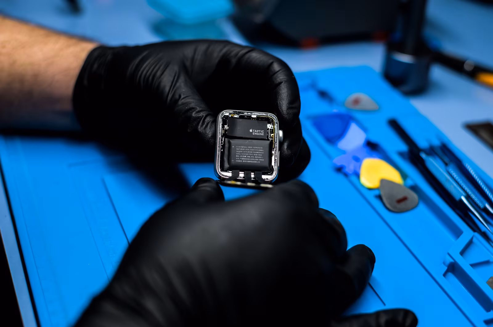 Technician opening a smartwatch on a repair bench with precision tools