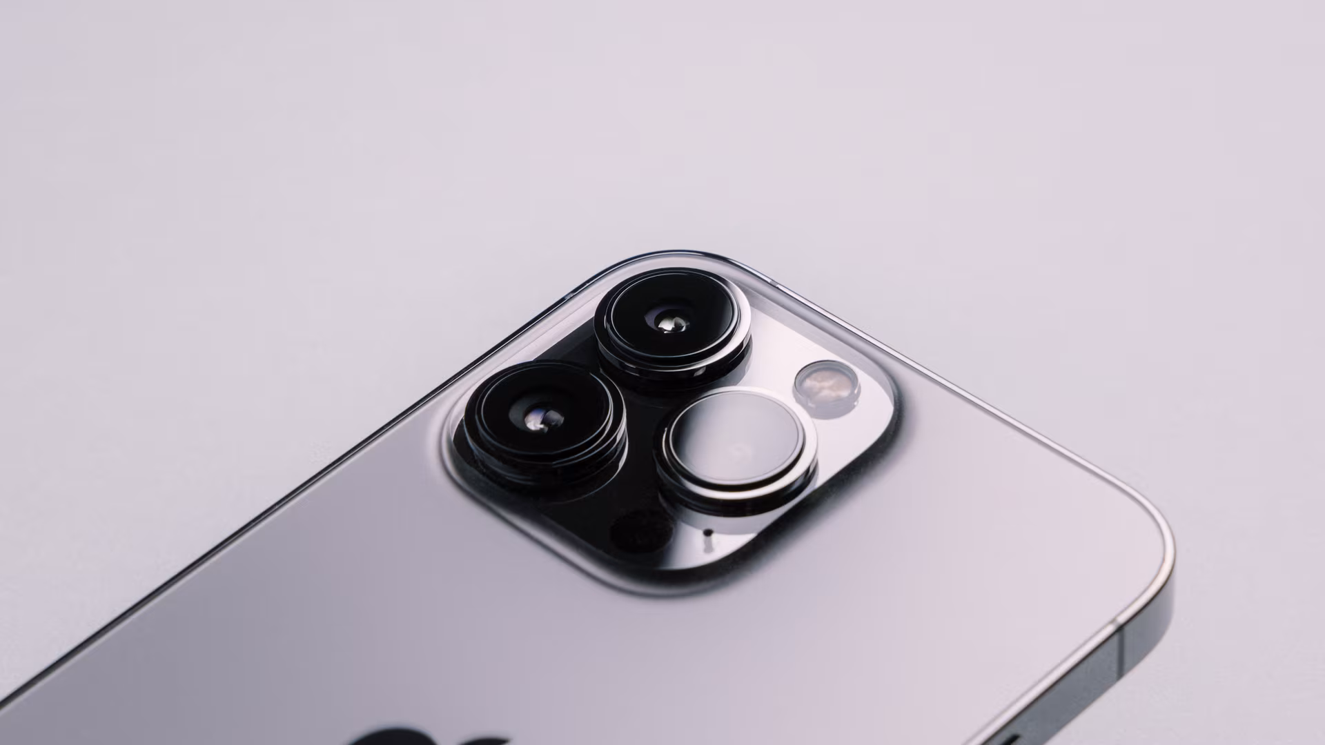Close-up of the rear camera lenses and lens covers on a silver iPhone Pro